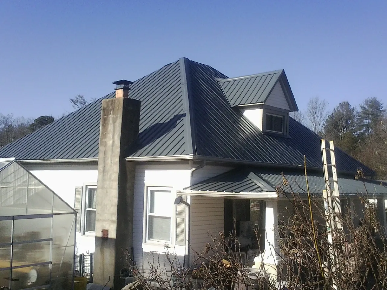 Dark blue standing seam metal roof on a white farmhouse with dormer — Slate & Tile Roof Repair by Roofing Brothers in Feeding Hills