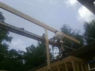 Carpenter setting a ridge beam over a new addition frame — Ice Dam Removal by Roofing Brothers in Feeding Hills
