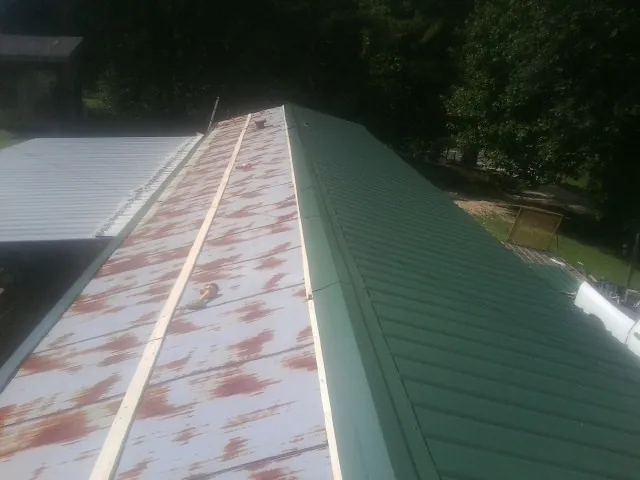 Old rusted panels beside newly installed green metal roofing — Wind Damage Roof Repair by Roofing Brothers in Feeding Hills