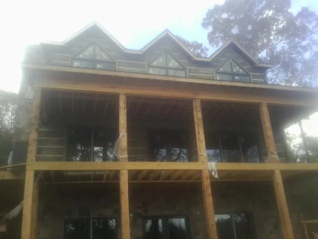 Dormers and porch framing on a large log home under construction — Roof Coating work by our crew in Feeding Hills