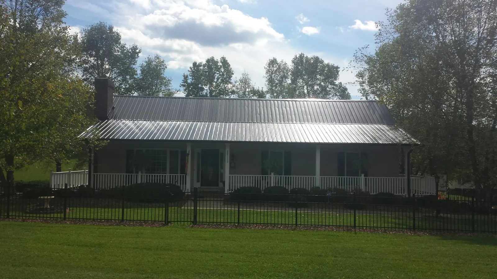 Gray metal roof on a brick ranch with a full width front porch — Gutter Guard Installation work by our crew in Feeding Hills