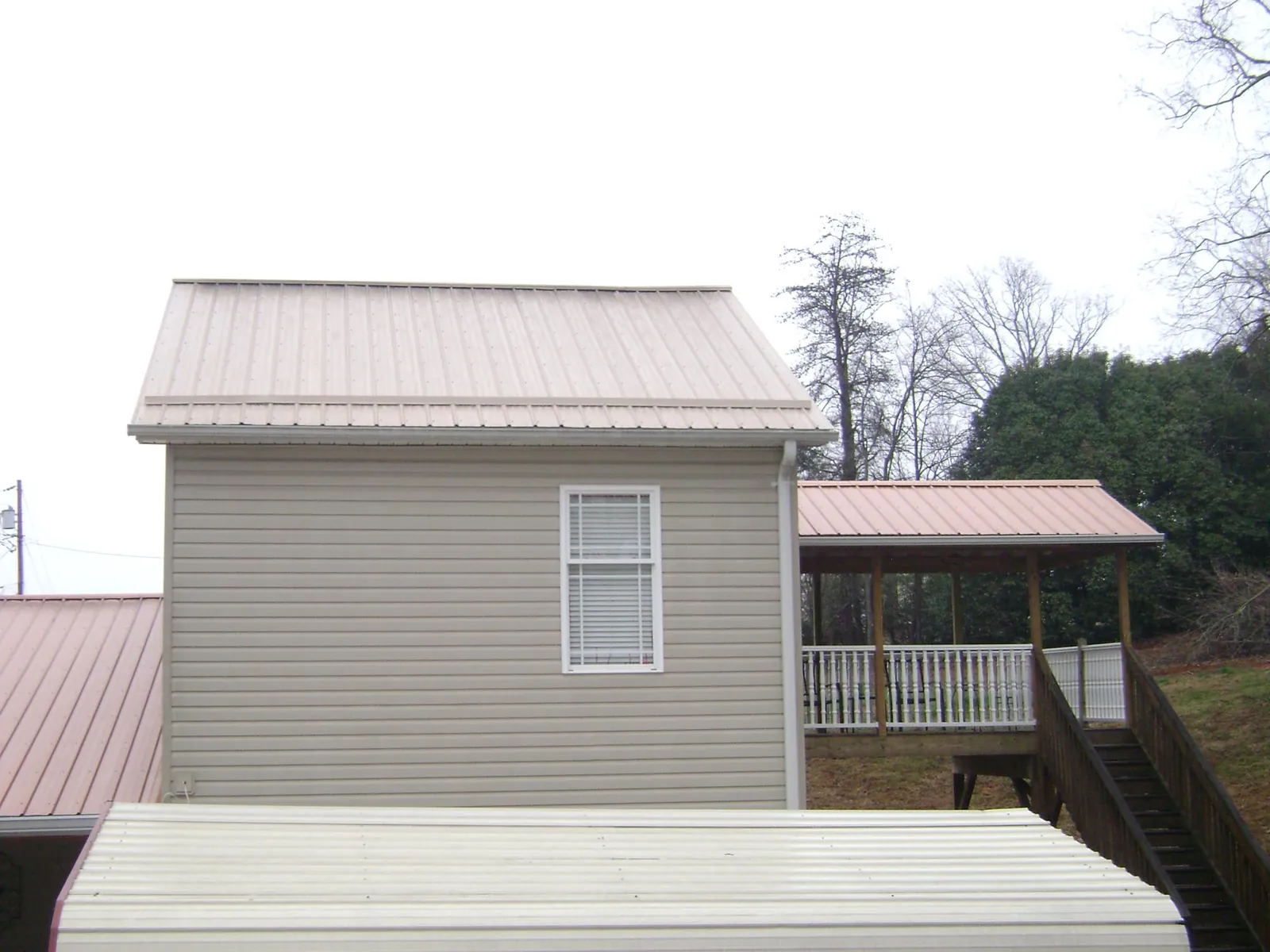 Tan metal roofs on a two story addition and attached porch, from a Roof Replacement job in Feeding Hills